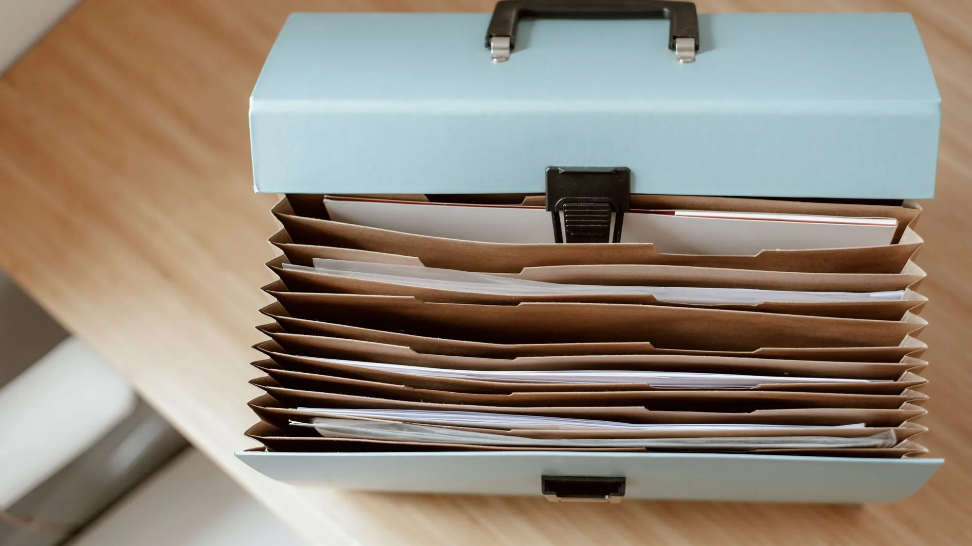 Carpeta de acordeón con documentos sobre un escritorio de madera