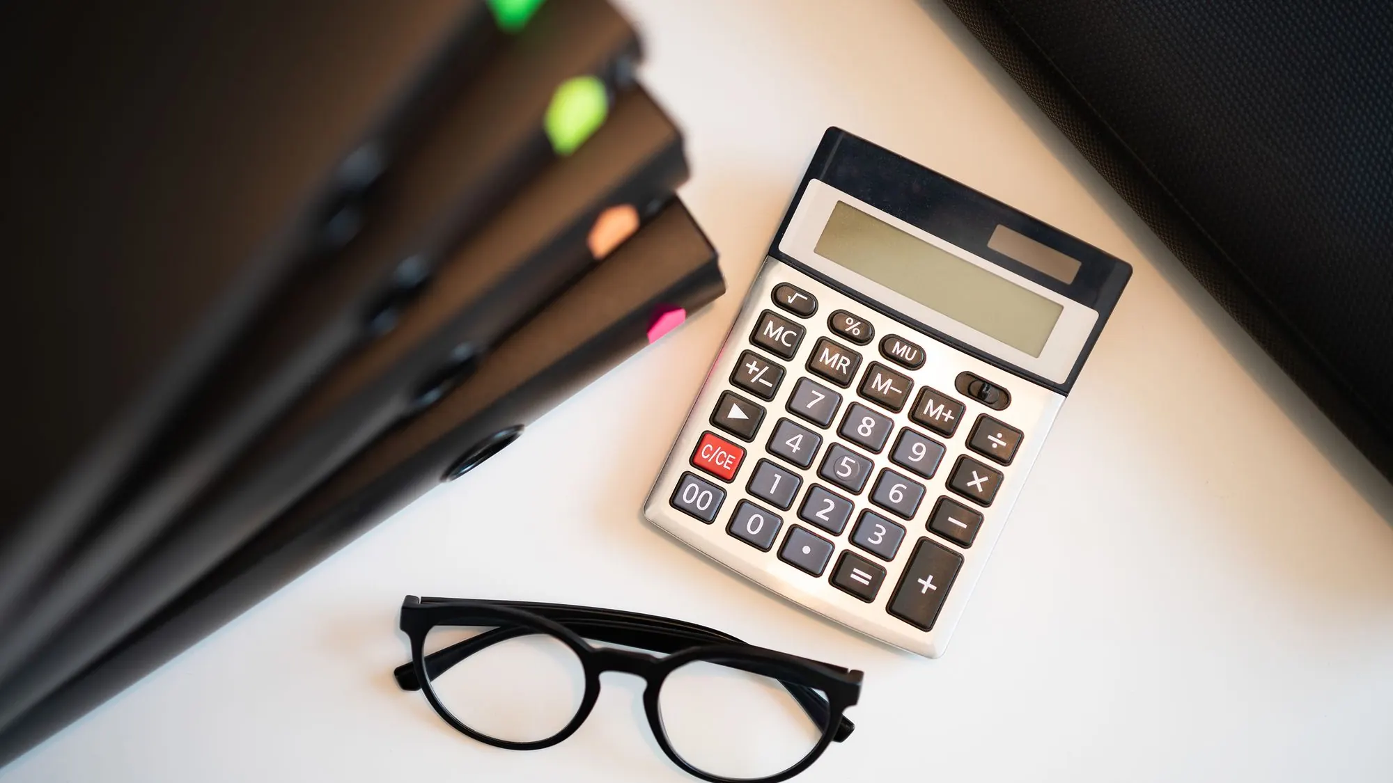 Calculadora, gafas y carpetas sobre la mesa de la oficina