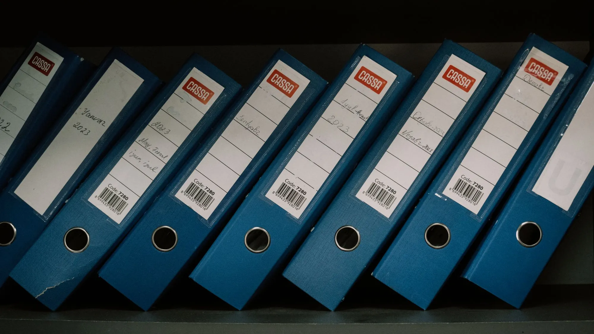 Archivadores etiquetados alineados en una estantería de oficina